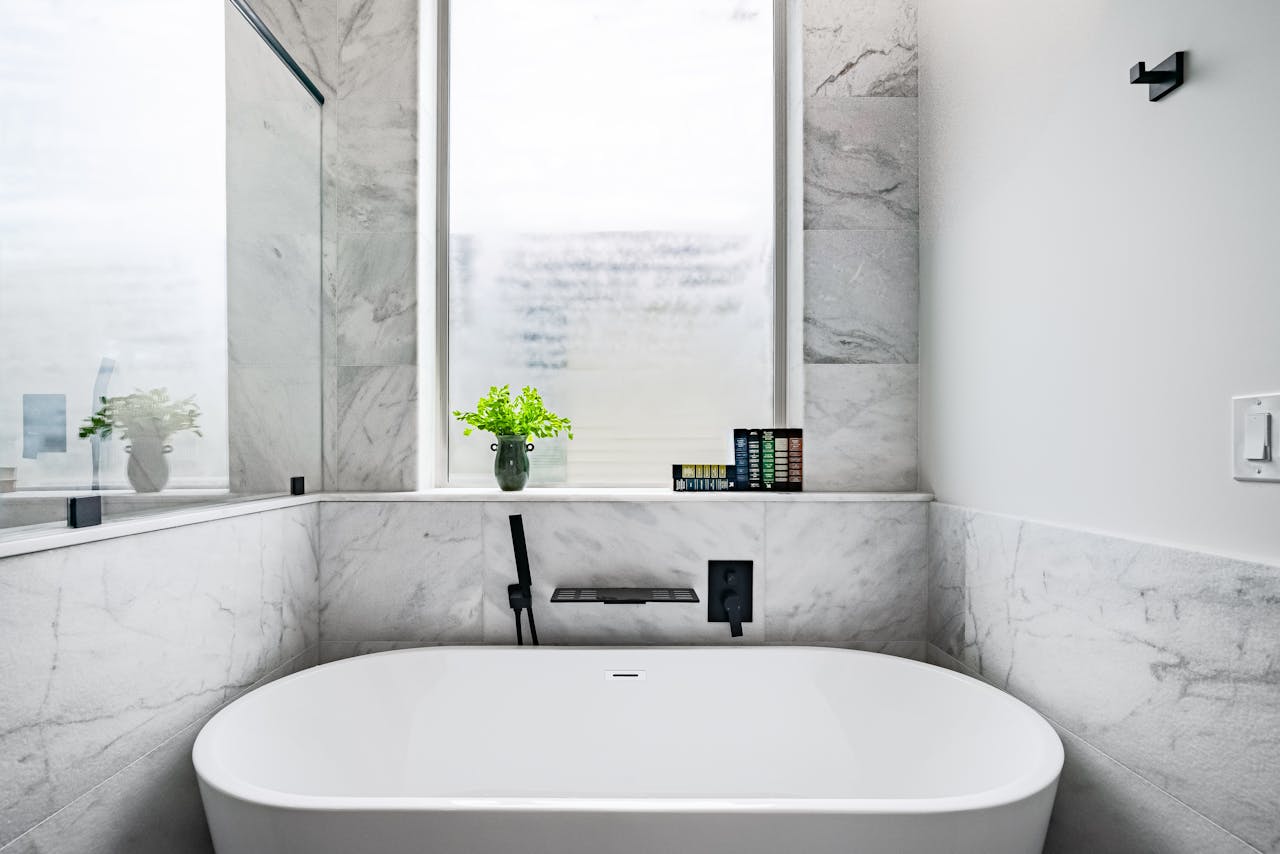 Luxurious marble bathroom featuring a stylish white bathtub and minimalist decor.